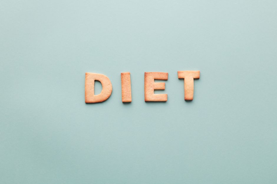'diet'라고 쓰인 알파벳 쿠키가 부드러운 청록색 배경에서 평면 배치로 촬영되었습니다.