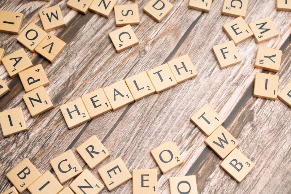 나무 표면에 'HEALTH'를 철자하는 스크래블 타일로 웰빙을 상징합니다.